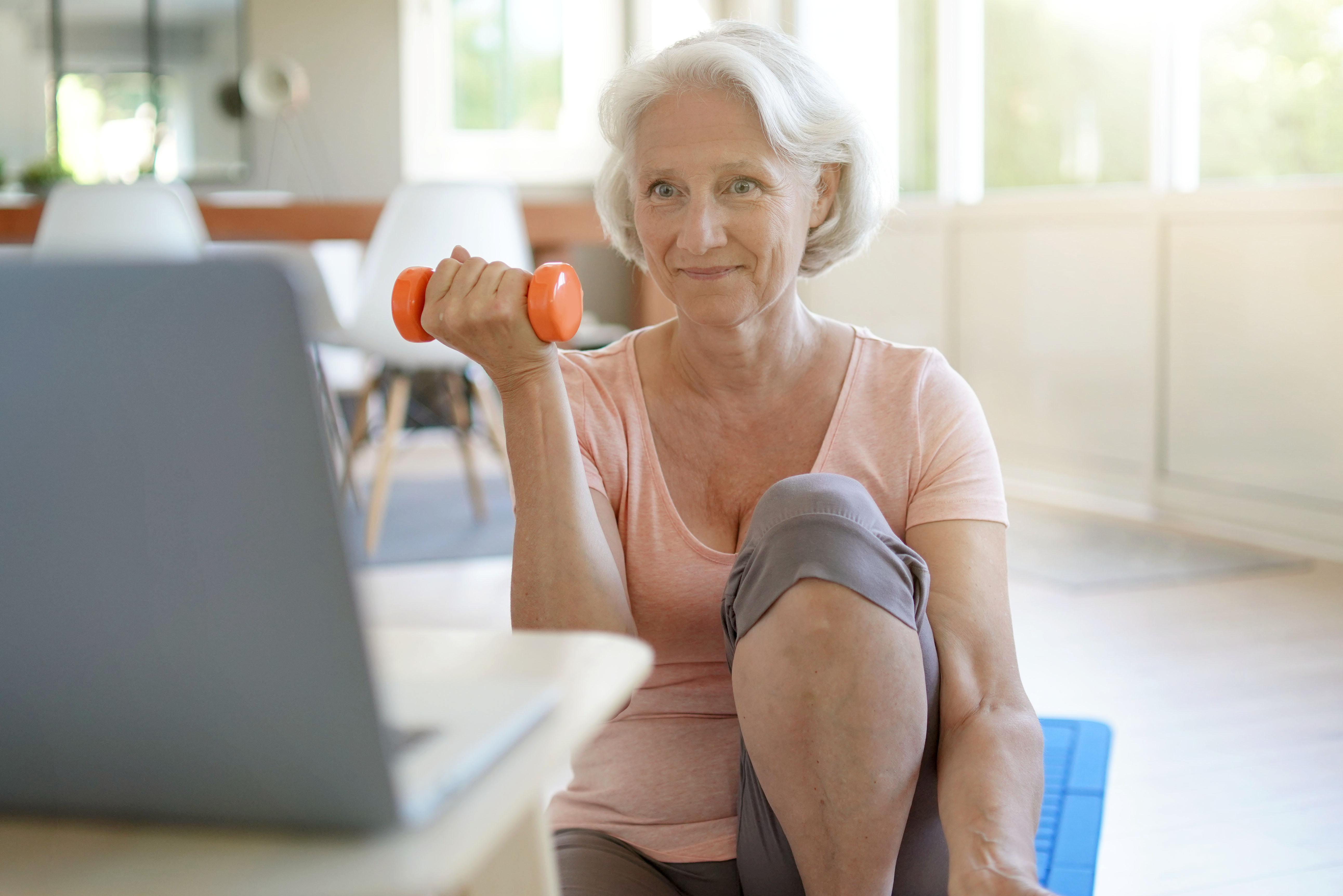 Senior woman doing fitness exercises at home through virtual class | goodluz - stock.adobe.com